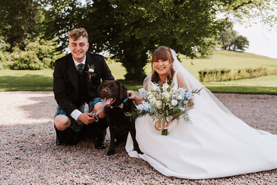 bride and groom kneeling down to have their photograph taken with their dog