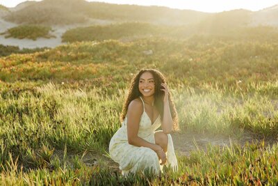 Senior girl in white dress smiling in golden hour light at Ventura Beach