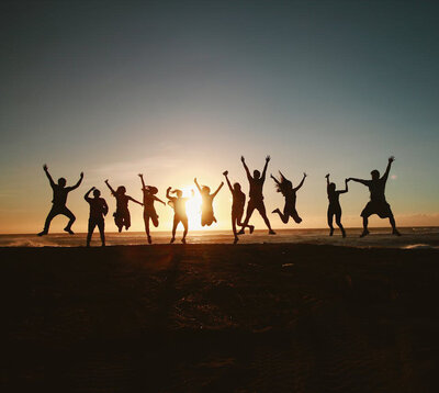 A group of people jumping and cheering in the air while overlooking the ocean.