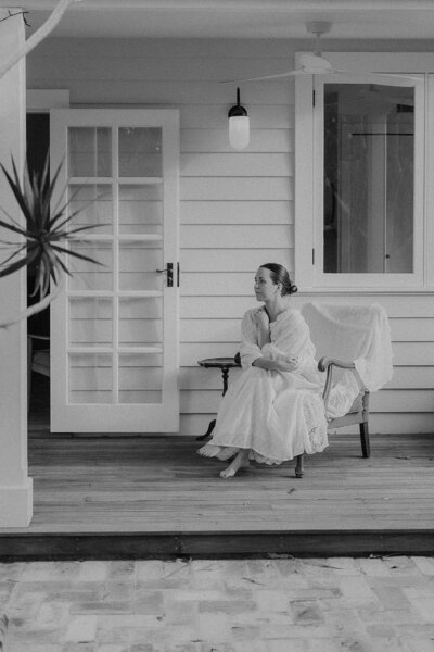 Kara in black and white on her front porch seated in a big wooden chair