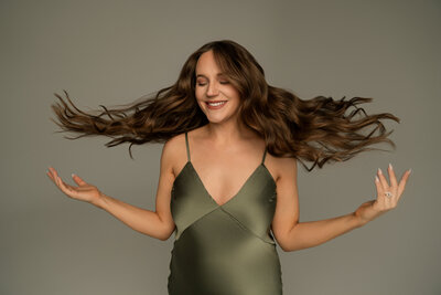 woman in a olive green dress swishing her hair to her sides