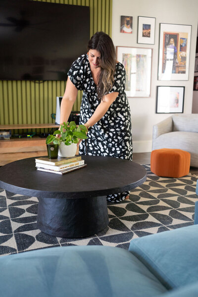 Online interior decorator, Michelle, wearing a black and white printed dress styling a coffee table