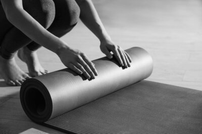Close-up of a woman rolling out a yoga or exercise mat on the floor, preparing for a workout.