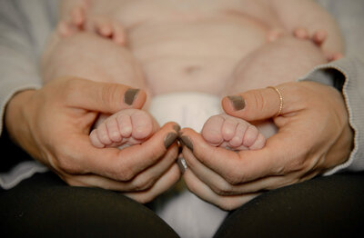 two hands holding baby feet