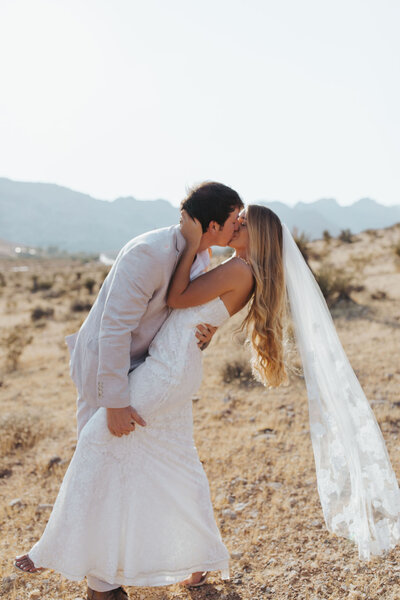 bride and groom kissing in desert