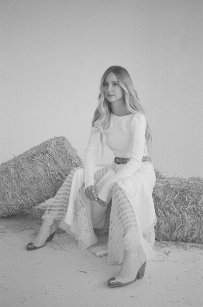 woman wearing all white while sitting on hay bales