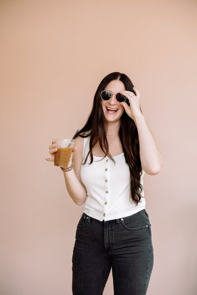 Melissa Stuckey holding a drink and wearing sunglasses laughing