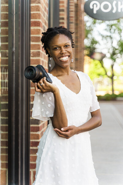 Lydia McRae smiling, holding her camera next to her shoulder