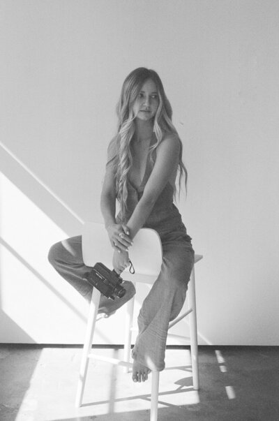 woman holding camera and sitting on a stool
