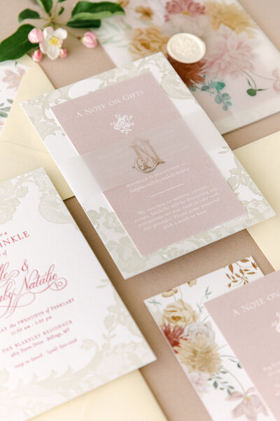 Letterpress baby shower invitation featuring shades of pink and butter yellow, with a vellum belly band, showcasing creative invitation ideas for a memorable event.