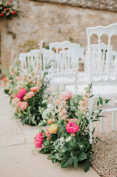Pink meadow-style floral arrangements lining the wedding ceremony aisle at Caswell House