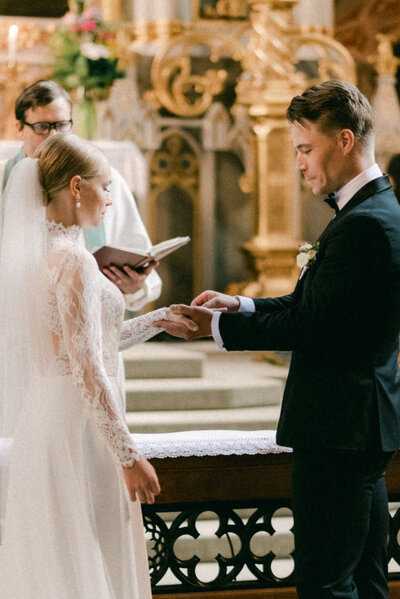Groom is putting the wedding ring on bride's finger during a wedding ceremony in Turku cathedral.  Documentary wedding photograph by wedding photographer Hannika Gabrielsson.