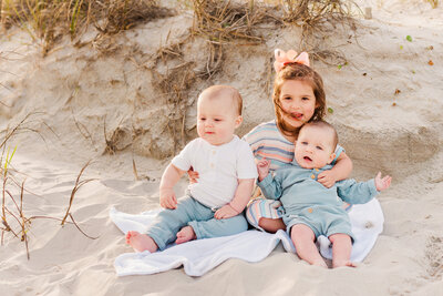 Cousins posing by sand dune for family photos with Ron Schroll Photography at Ocean Isle Beach, NC