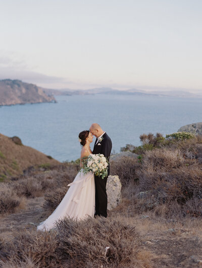 couple getting married on a cliff with pampas grass ceremony arch