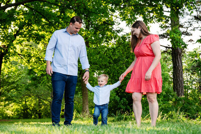 st-louis-mini-sessions-mom-and-dad-holding-babys-hands-in-spring-season-at-forest-park