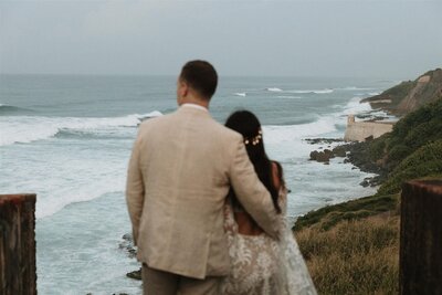 bride and groom looking out over coastal cliffs