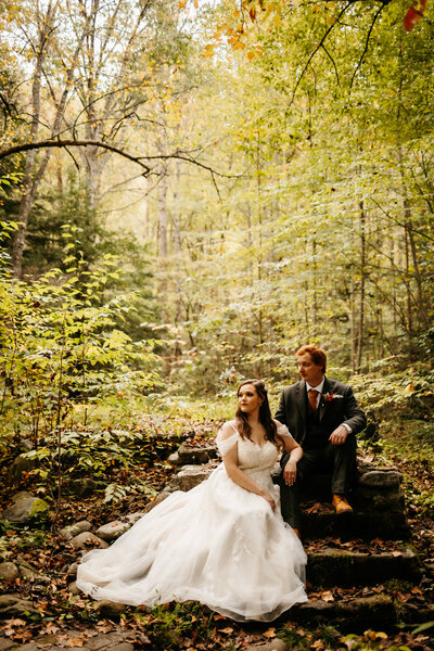 photographers in gatlinburg tn captures couple eloping to Gatlinburg in Cades Cove with groom carrying his bride through a meadow as her gown flows in the wind 