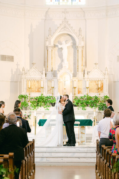 bride and groom kissing at their sacred heart catholic church ceremony