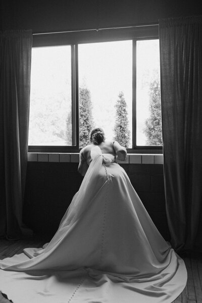 black and white photo of bride looking out window