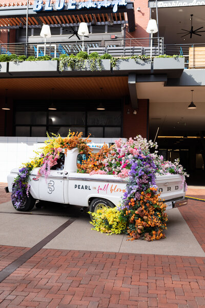 Cheerful pickup truck installation composed of silk floral hues in pink, magenta, lavender, coral, orange, yellow, and mixed greens bring to life this spring Fifth + Broadway event in Nashville, TN. Design by Rosemary and Finch.