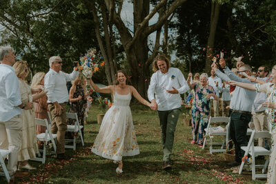 A joyful and candid wedding photo - the classic confetti shot of a bride and groom coming back down the aisle, from their wedding near Bellingen