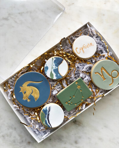 Six vanilla almond sugar cookies with capricorn decor in a box.