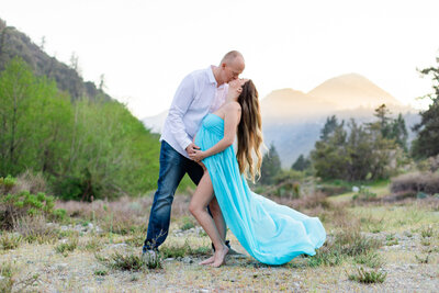 mom and dad kiss with floating maternity dress