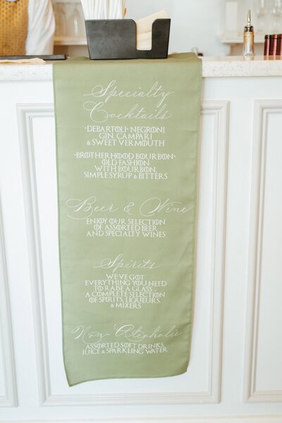Sage green wedding banner with writing on it.