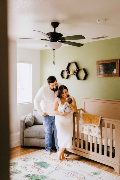Couple holding their newborn baby in her nursery for an in-home lifestyle newborn photography session. 
