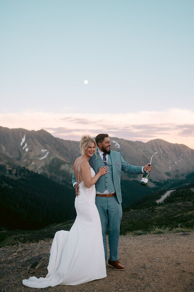 Bride and Groom popping champagne on mountain