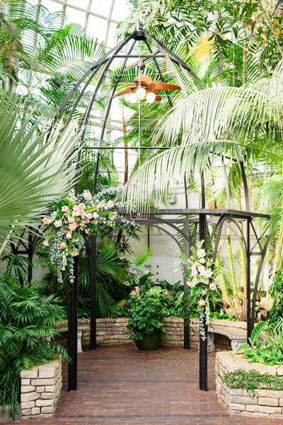 A large pastel floral arrangement hangs over the altar inside the Palm House at the Franklin Park Conservatory in Columbus
