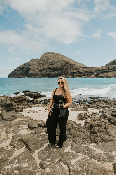 Maui Elopement Photographer captures woman standing on rocks holding camera