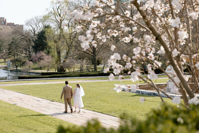 Bride and groom walking around Wade Lagoon in Cleveland during spring.