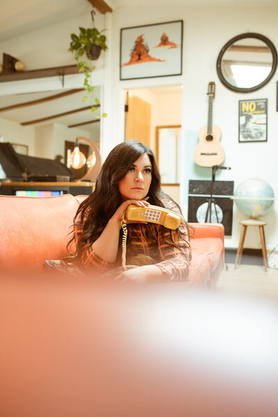 woman holding vintage phone on orange couch