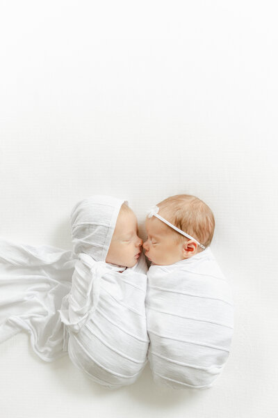newborn twins swaddled in white lay next to eachother with noses touching, Indianapolis newborn photography