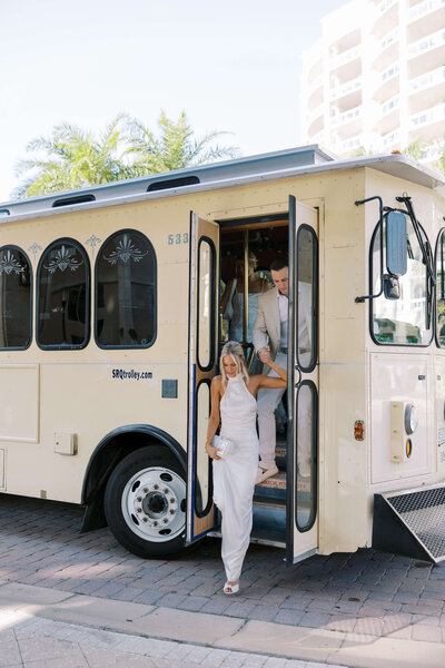 Bride and groom walking off bus into their welcome party