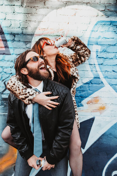 Man Giving Woman Piggyback Against Graffiti Wall