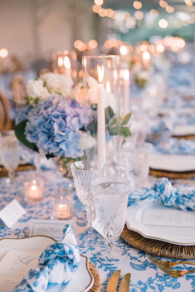 blue and white flowers on a reception guest table with candles and votives