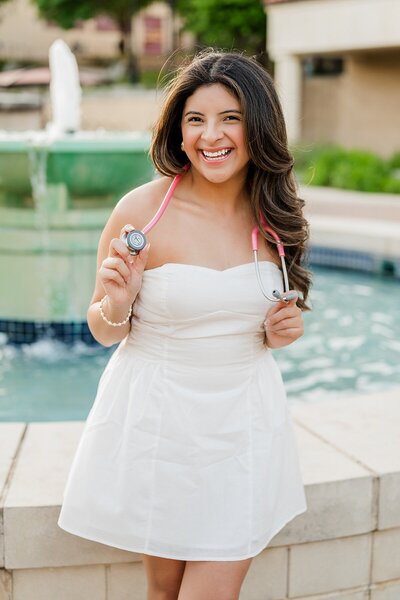 Texas State grad posing in front of the fountain 
