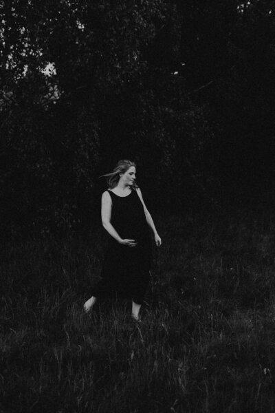en gravid kvinna i linneklänning dansar på en äng