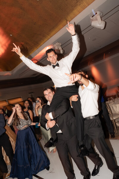 a groom being lifted up on the dance floor of his wedding reception