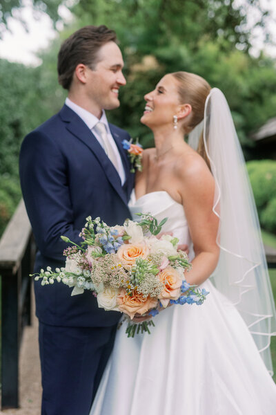 bride and groom looking at each other while smiling and holding a bridal bouquet at Fort Worth Botanic Gardens by Kortney Boyett Photography
