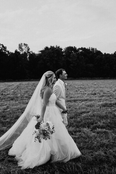 Black and white of bride and groom holding hands outside in Wedding Photography Minneapolis. 
