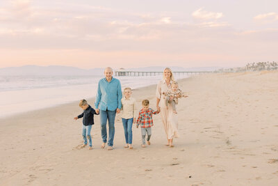 Family walking along the beach together on a peaceful morning with kids playing in the sand.