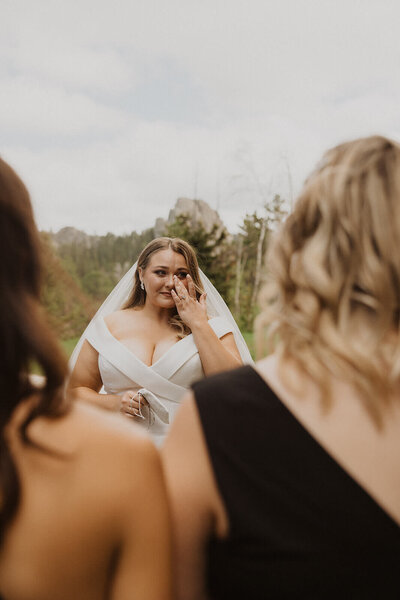 Bride wipes away her tears during first look with her bridesmaids