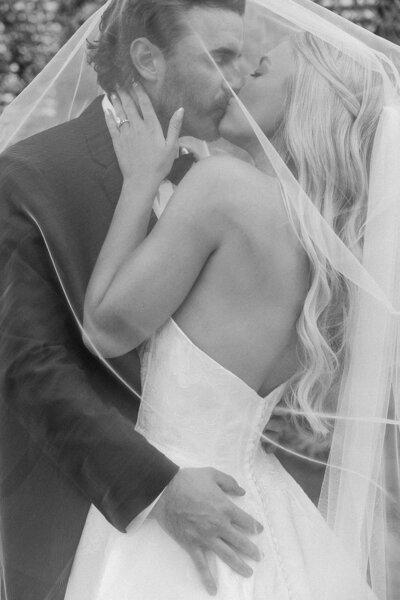 Bride and groom kissing under the veil in black and white at Germantown Gables in Louisville KY