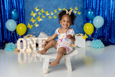 Birthday girl smiles on a blue and yellow themed set
