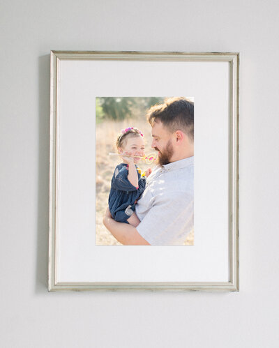 A framed portrait of a  young girl being held by her father.