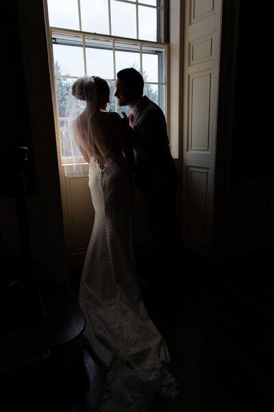 Bride and groom standing in front a window