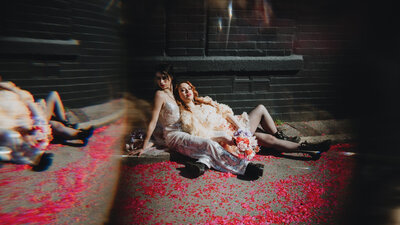 Female bridal couple laying on the confetti covered ground